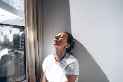 Portrait of a dreadlock braid woman sitting by the open window at the white wall