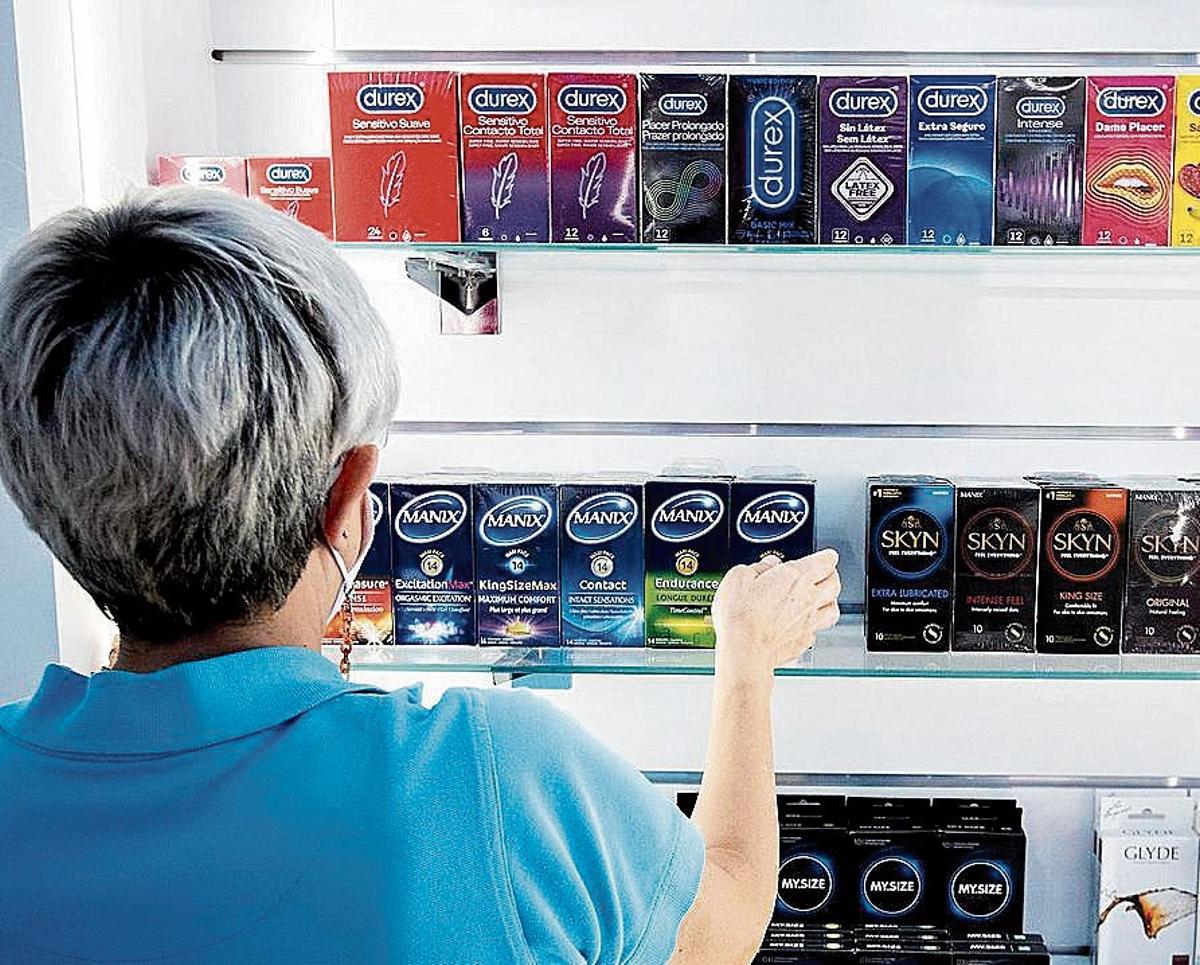 Una empleada coloca cajas de preservativos en una tienda.